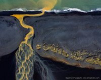 Aerial photo of yellow river flowing through a black lava beach, Iceland