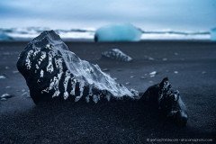 Glacier ice covered in black lava sand, Diamond beach Iceland