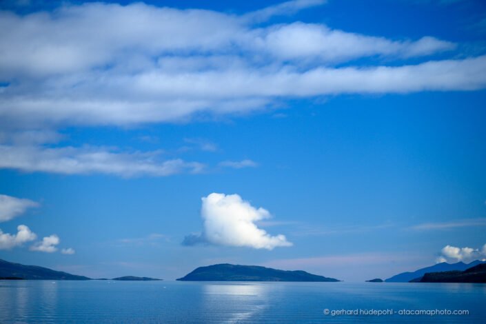 A single cloud stands out above a Patagonian fjord.